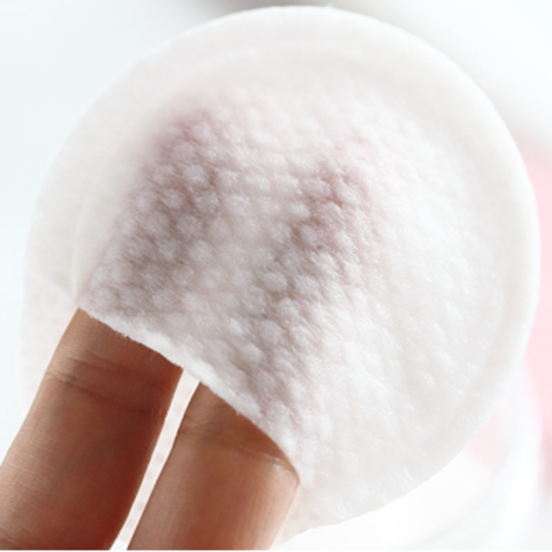 Nahaufnahme einer Hand, die ein weißes, strukturiertes Kosmetikpad hält.