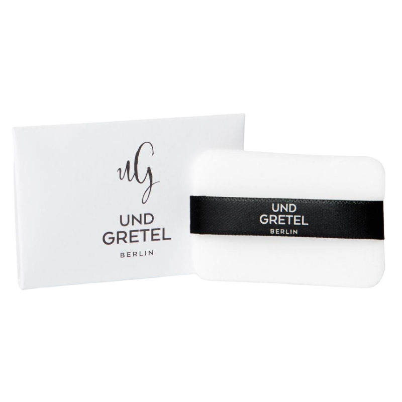 UND-GRETEL-ILGE-TRANSLUCENT-COMPACT-POWDER-PUFF UND GRETEL ILGE Translucent Compact Powder Puff vor weißem Hintergrund, mit schwarzem Band und Verpackung.