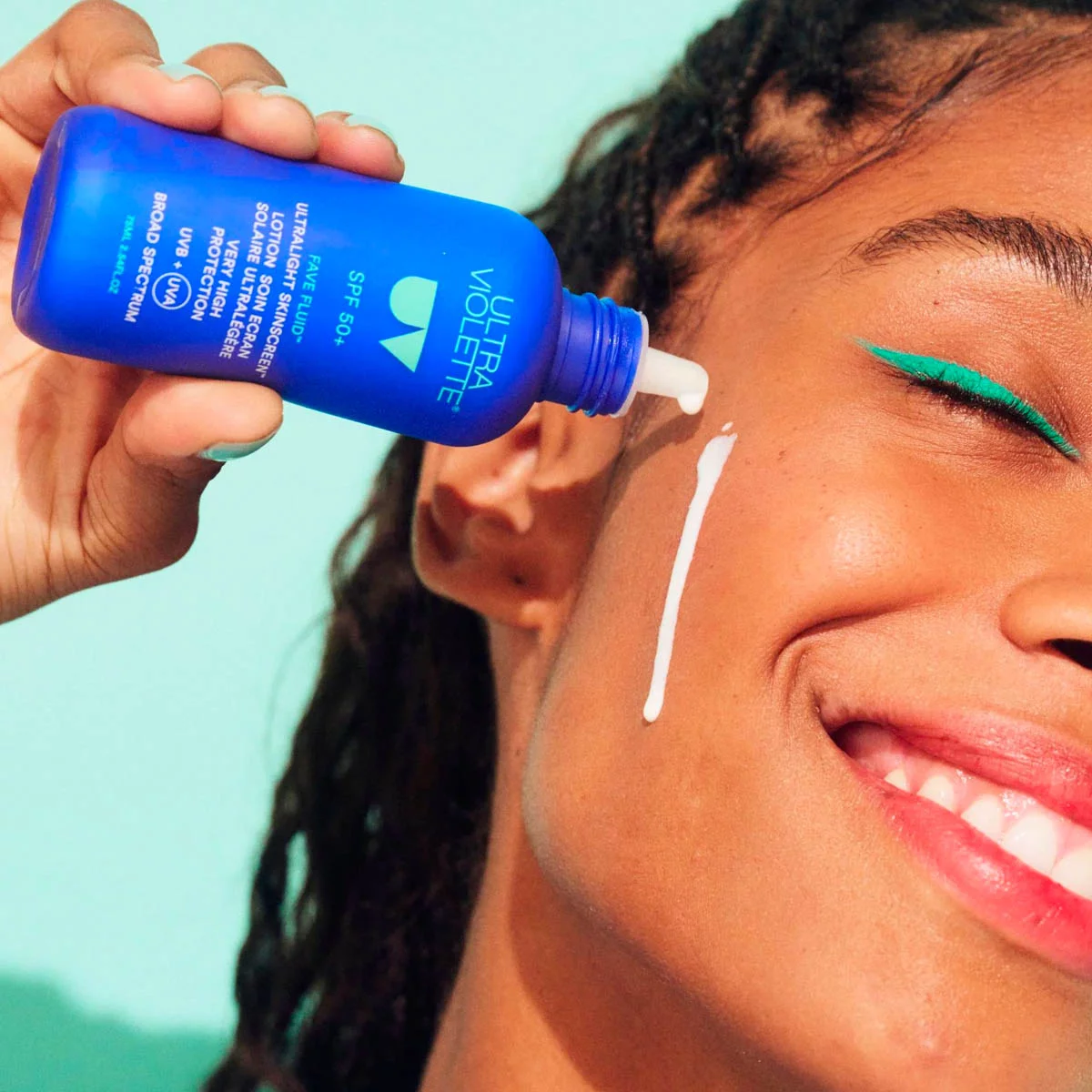 ULTRA-VIOLETTE-Fave-Fluid-SPF-50-plus-Sunscreen-Anwendung Frau trägt ULTRA VIOLETTE Fave Fluid SPF 50+ Sonnencreme auf ihr Gesicht auf.