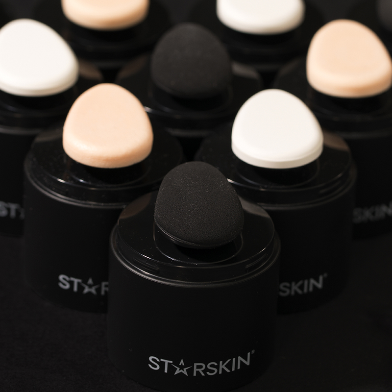 Mehrere STARSKIN Make-up-Schwämme in verschiedenen Farben auf schwarzen Halterungen.